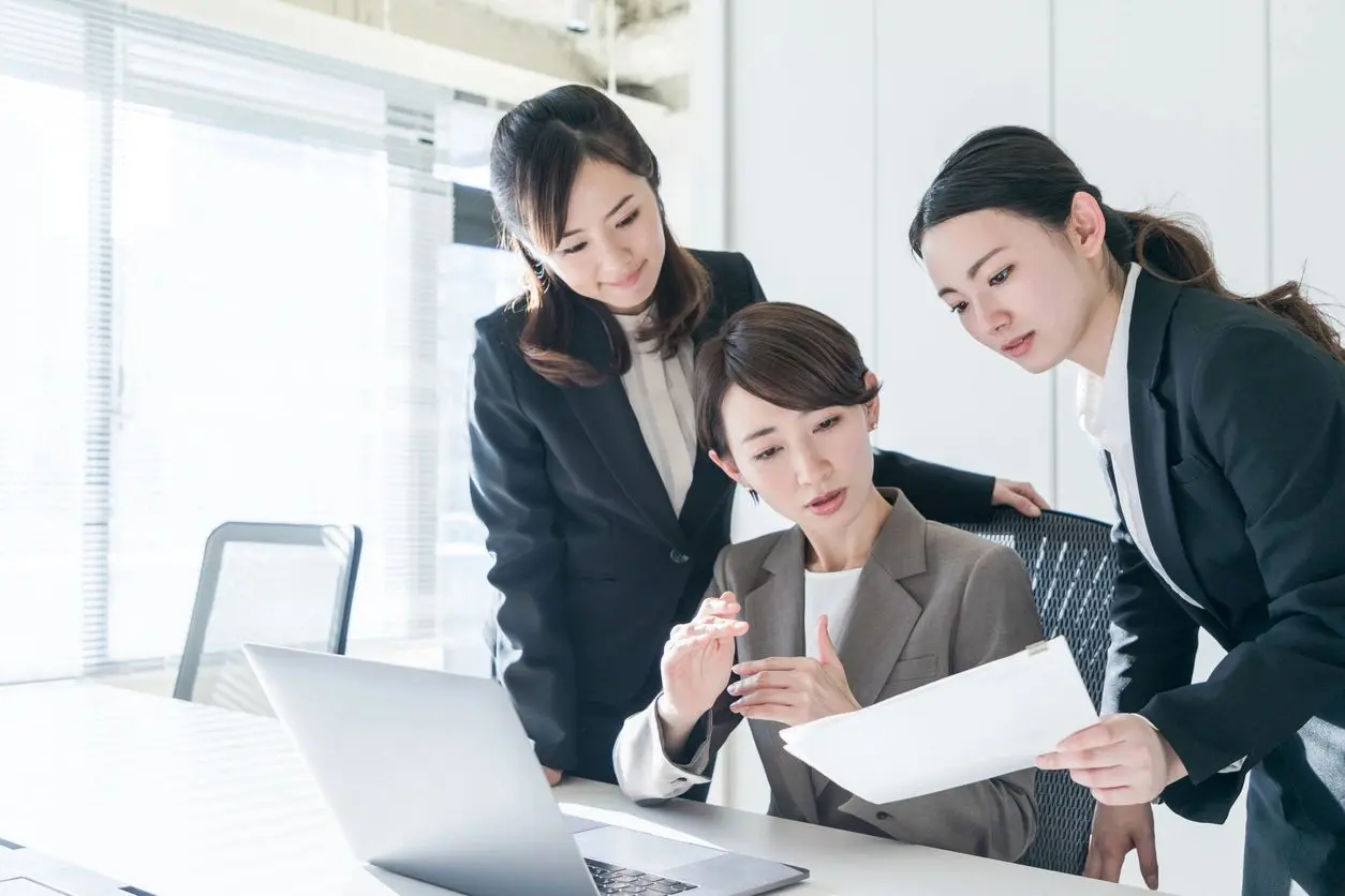 Three women are looking at a laptop screen.